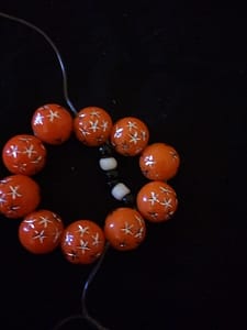 Thread at the fourth orange bead