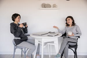 Two ladies holding mugs as they communicate (trust) 